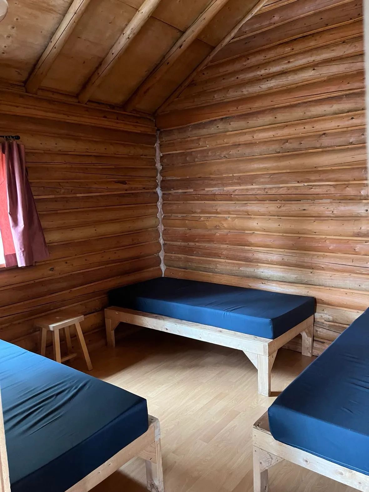Vue intérieure de la chambre du chalet avec ses murs en bois rond et ses lits simples.