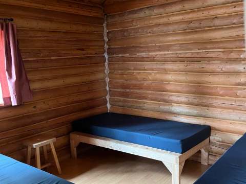 Vue intérieure de la chambre du chalet avec ses murs en bois rond et ses lits simples.
