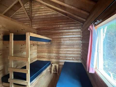 Cette chambre rustique du chalet comprend des lits superposés et un lit simple.
