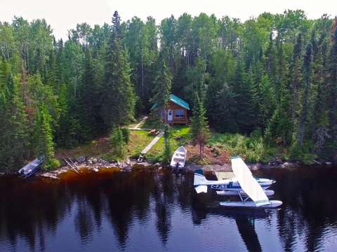 Vue aérienne du chalet niché en bordure de forêt avec accès direct par hydravion.