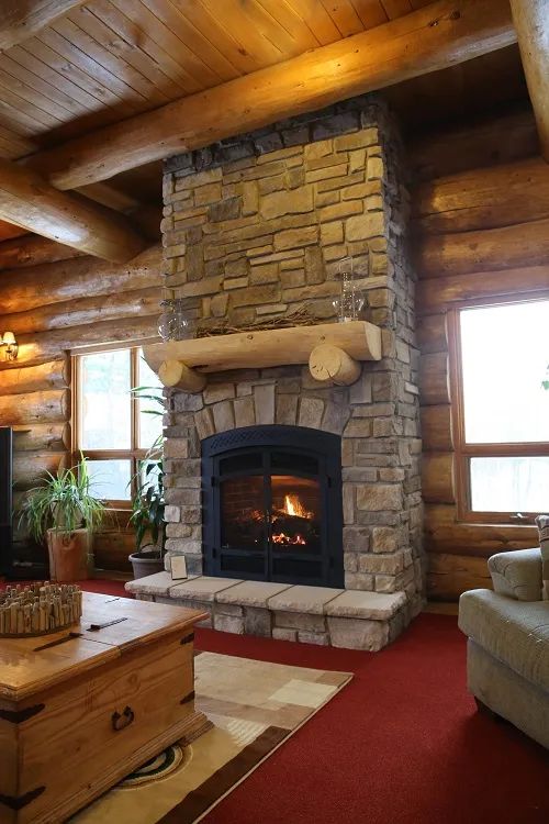 The inn's cozy living room features a stone fireplace and log walls.