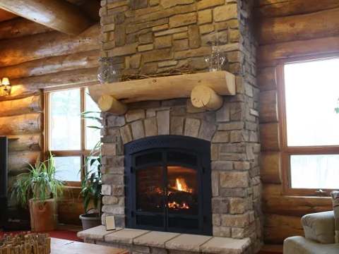 The inn's cozy living room features a stone fireplace and log walls.