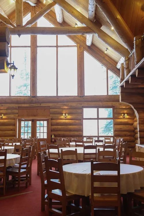 The main dining room offers a vast, warm space with its log walls.