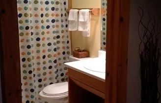 The inn's private bathroom features a sink and a shower with a colorful curtain.
