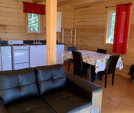 L'aire ouverte du chalet comprend une cuisine équipée, une table à manger et un canapé en cuir.