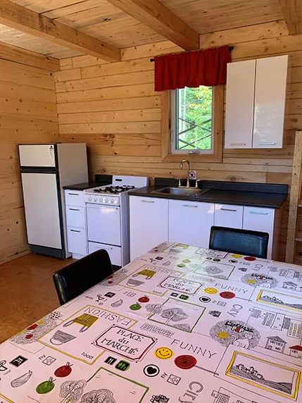 La cuisine fonctionnelle du chalet comprend une cuisinière, un réfrigérateur et un coin repas.