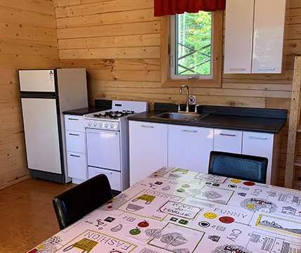 La cuisine fonctionnelle du chalet comprend une cuisinière, un réfrigérateur et un coin repas.