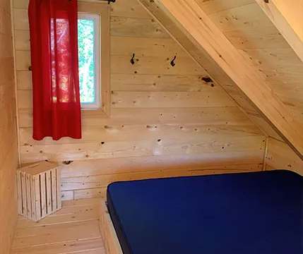 Coin chambre mansardé avec lit simple dans le chalet.