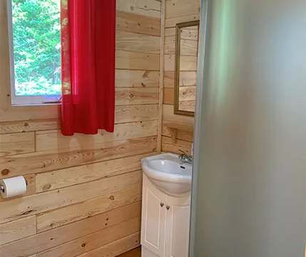 Cette salle de bain de chalet est équipée d'une douche, d'un lavabo et de murs en bois naturel.