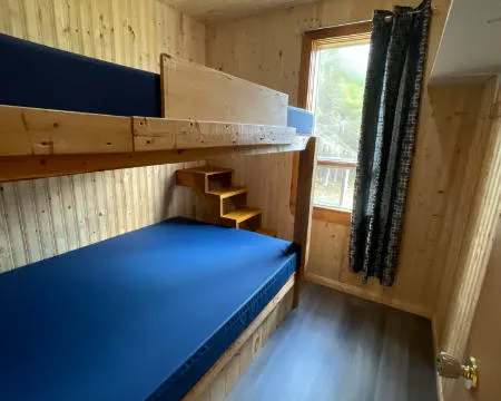 Cette chambre du chalet comprend des lits superposés en bois avec des matelas bleus.