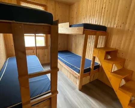 Cette chambre du chalet 2 comprend deux lits superposés en bois avec des matelas simples.