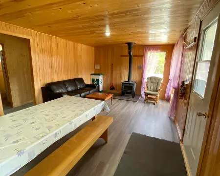 L'aire de vie principale du chalet comprend une table à manger, un coin salon et un poêle à bois.