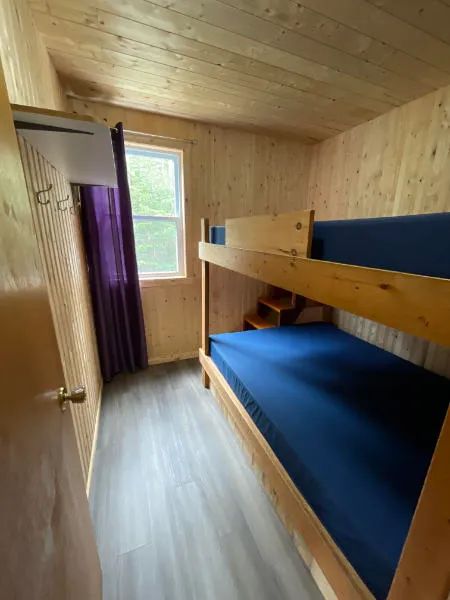 Cette chambre comporte un lit superposé en bois dans un intérieur aux murs lambrissés.
