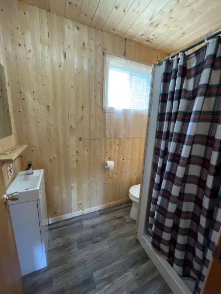 Vue de la salle de bain du chalet 3 avec ses murs en lambris de bois et sa douche fermée.