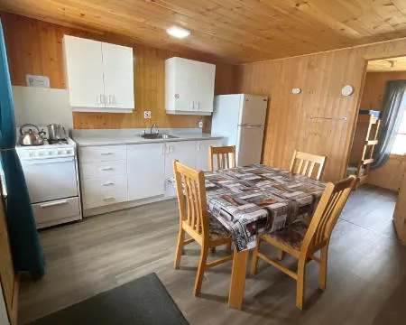 La cuisine équipée et l'espace repas du chalet 4 offrent une ambiance chaleureuse en bois.