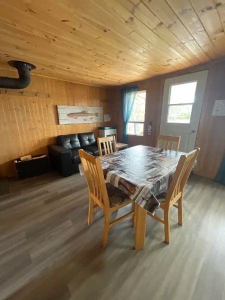 Coin repas et salon aménagés dans le chalet, avec murs lambrissés en bois.