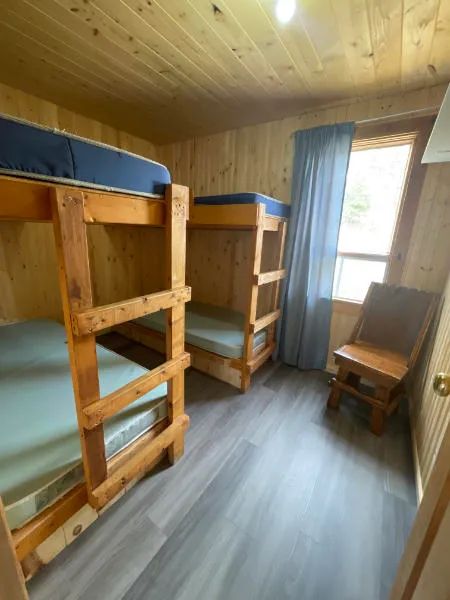 Cette chambre du chalet comprend deux lits superposés en bois et une chaise.