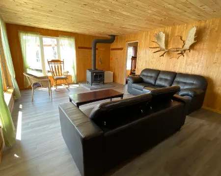 Le salon du chalet 7 offre des sofas en cuir et un poêle à bois pour vos moments de détente.