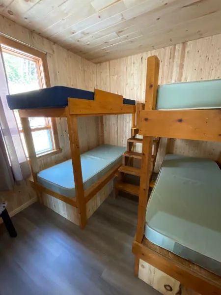 Cette chambre du chalet 7 est équipée de lits superposés en bois avec matelas simples.