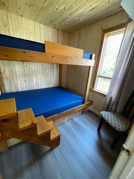 Cette chambre du chalet comprend un lit superposé en bois avec des matelas bleus.