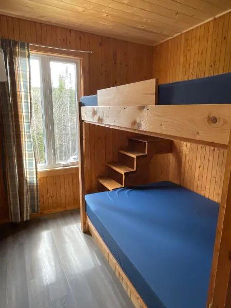 Cette chambre du chalet 8 est équipée d'un lit superposé en bois avec vue sur la forêt.