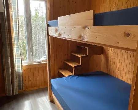 Cette chambre du chalet 8 est équipée d'un lit superposé en bois avec vue sur la forêt.