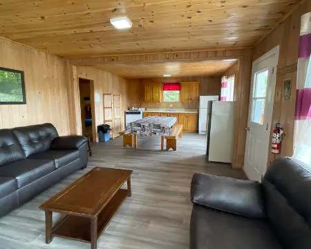 Vue d'ensemble de l'aire de vie principale du chalet, incluant le salon et la cuisine fonctionnelle.