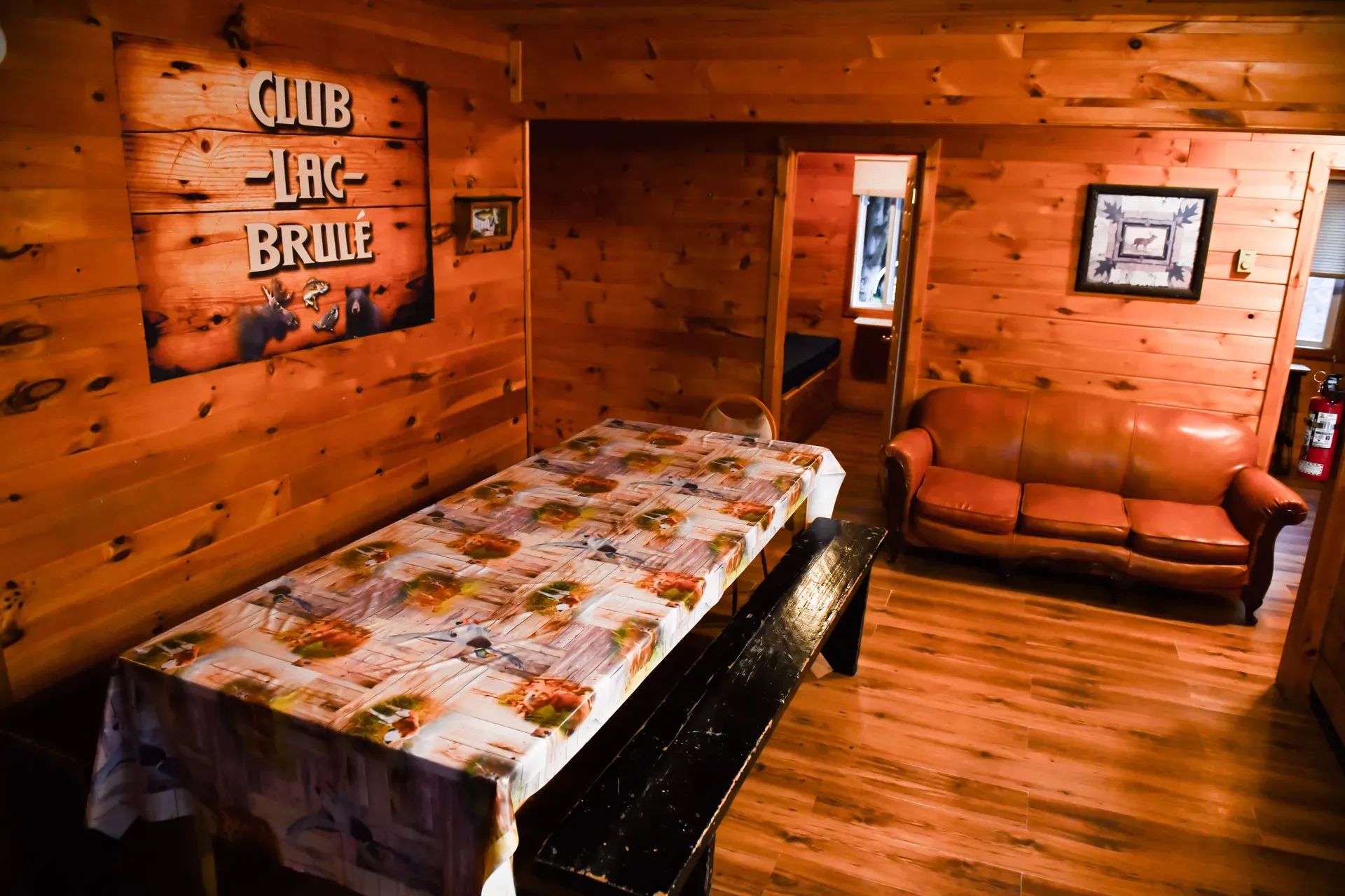 The cabin interior features a common area with a dining table and a leather sofa.