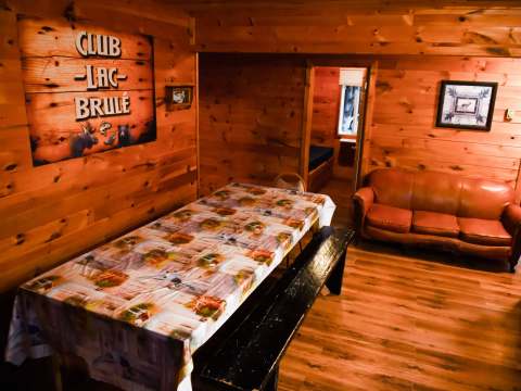 The cabin interior features a common area with a dining table and a leather sofa.