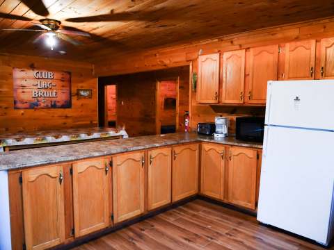 The cottage's fully equipped kitchen features wooden cabinets, a refrigerator, and a functional counter.