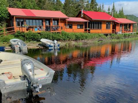 Vue sur les chalets en bois avec toits rouges bordant le rivage et les embarcations.