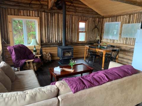 Le salon chaleureux du chalet dispose d'un poêle à bois et d'une aire de repas.
