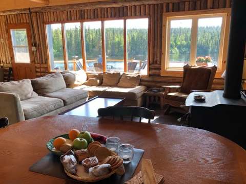 Le salon et la salle à manger du chalet offrent une vue lumineuse sur le lac et la forêt.