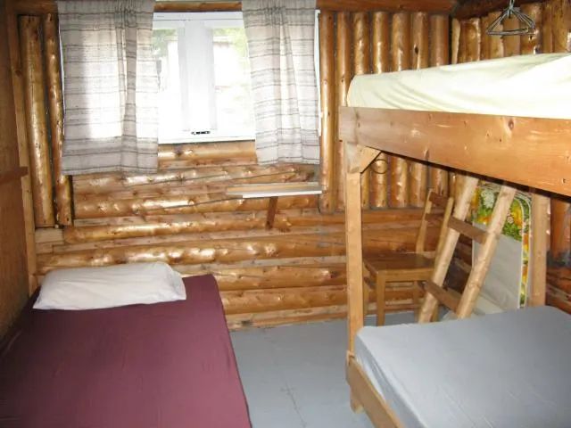 This rustic log room features single beds and a bunk bed.