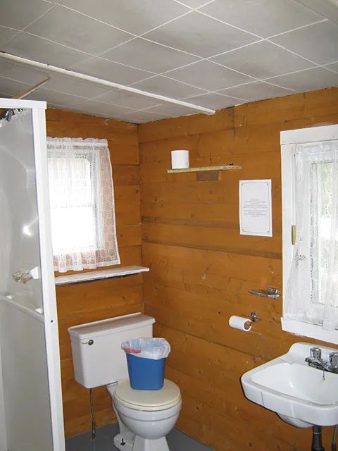 View of the functional bathroom with shower, toilet and sink in cabin number four.
