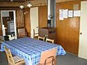 The cottage dining area features a table with chairs and a wood stove.