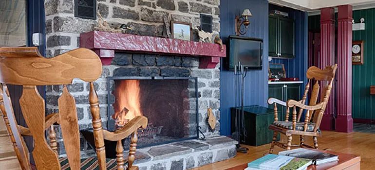 The main house living room features a stone fireplace and rocking chairs.