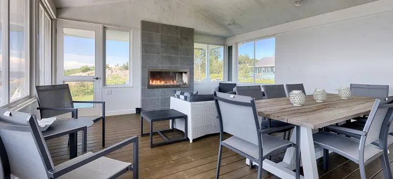This screened-in porch features a dining table and a lounge area with a built-in fireplace.