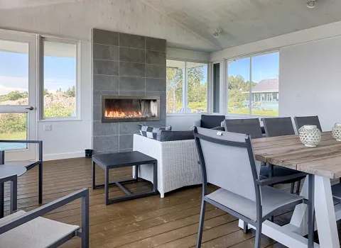 This screened-in porch features a dining table and a lounge area with a built-in fireplace.