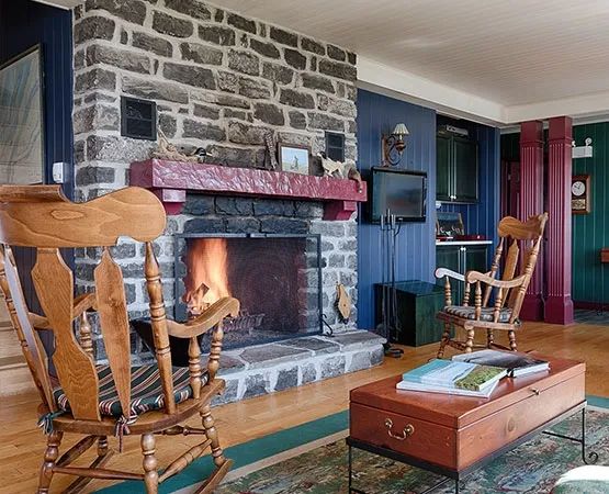 The main house living room features a stone fireplace and comfortable rocking chairs.