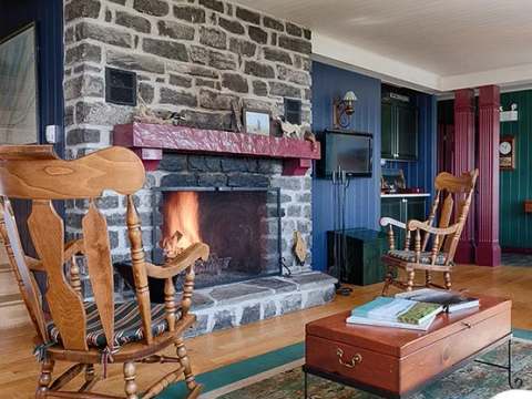 The main house living room features a stone fireplace and comfortable rocking chairs.