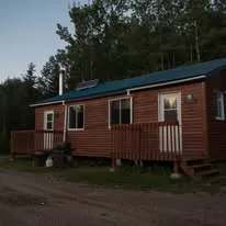 Vue extérieure du chalet Butor avec sa galerie en bois en fin de journée.
