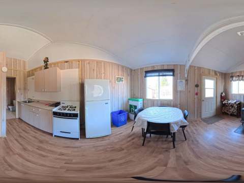 Panoramic view of the open concept living area including the kitchen, dining space, and wood stove.