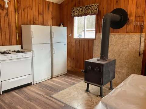 The Hirondelle cabin kitchen is equipped with a stove, refrigerators, and a wood stove.