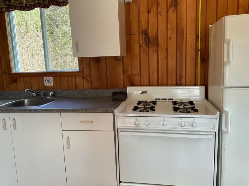 The functional kitchen of the Colibri cottage includes a stove, a refrigerator, and a sink.
