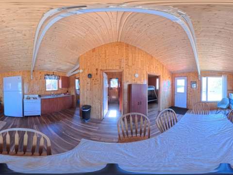 Vue panoramique de l'aire ouverte comprenant la cuisine, la salle à manger et le salon du chalet Héron.