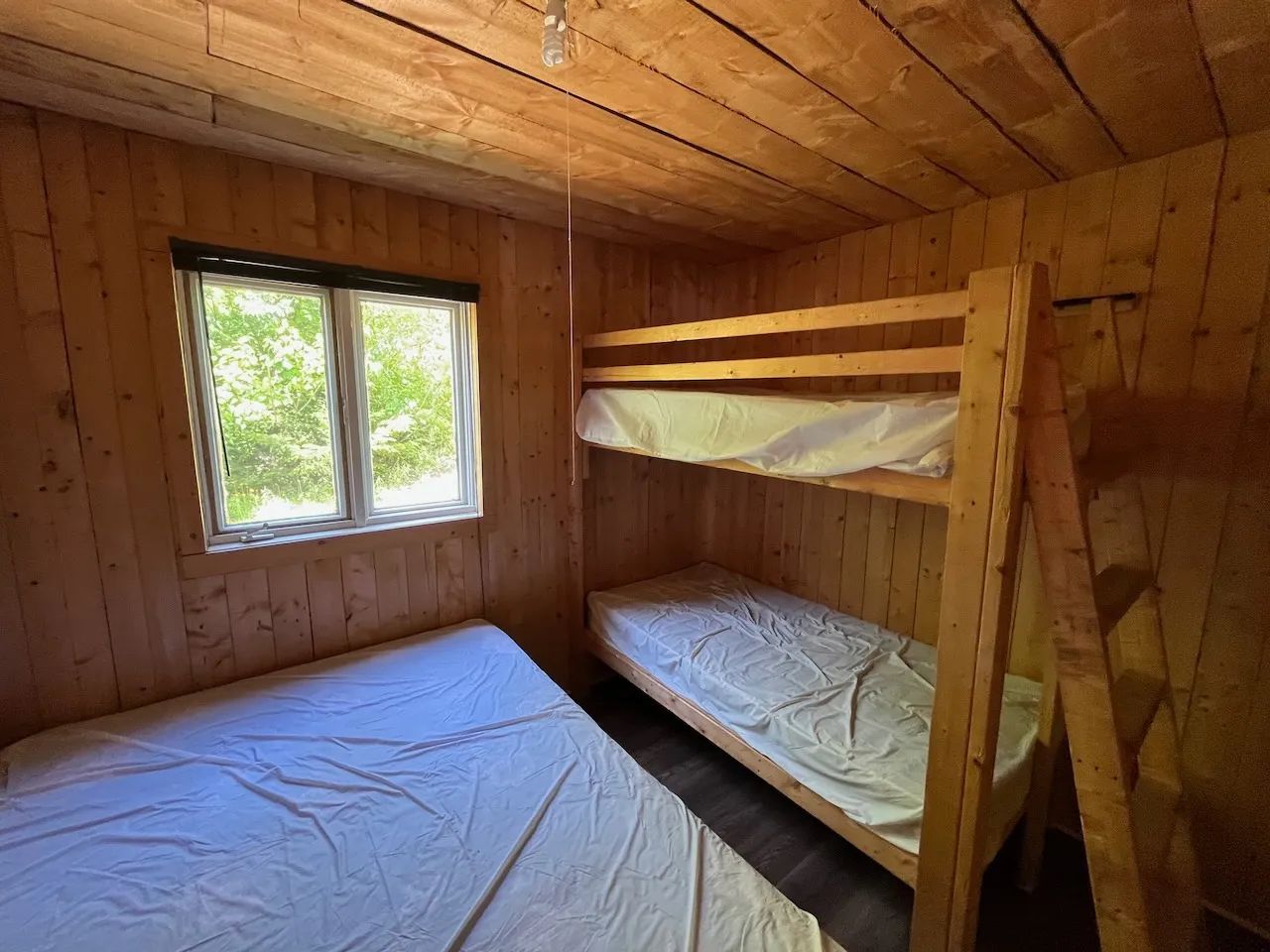 This bedroom in the Pygargue cottage features a single bunk bed and a double bed.