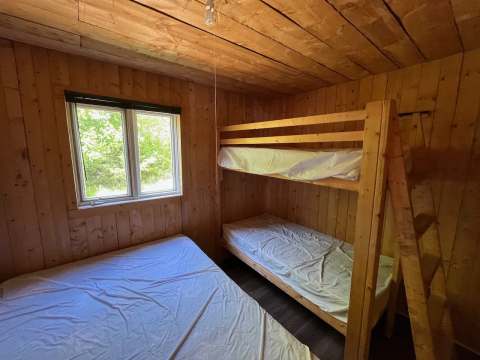 This bedroom in the Pygargue cottage features a single bunk bed and a double bed.