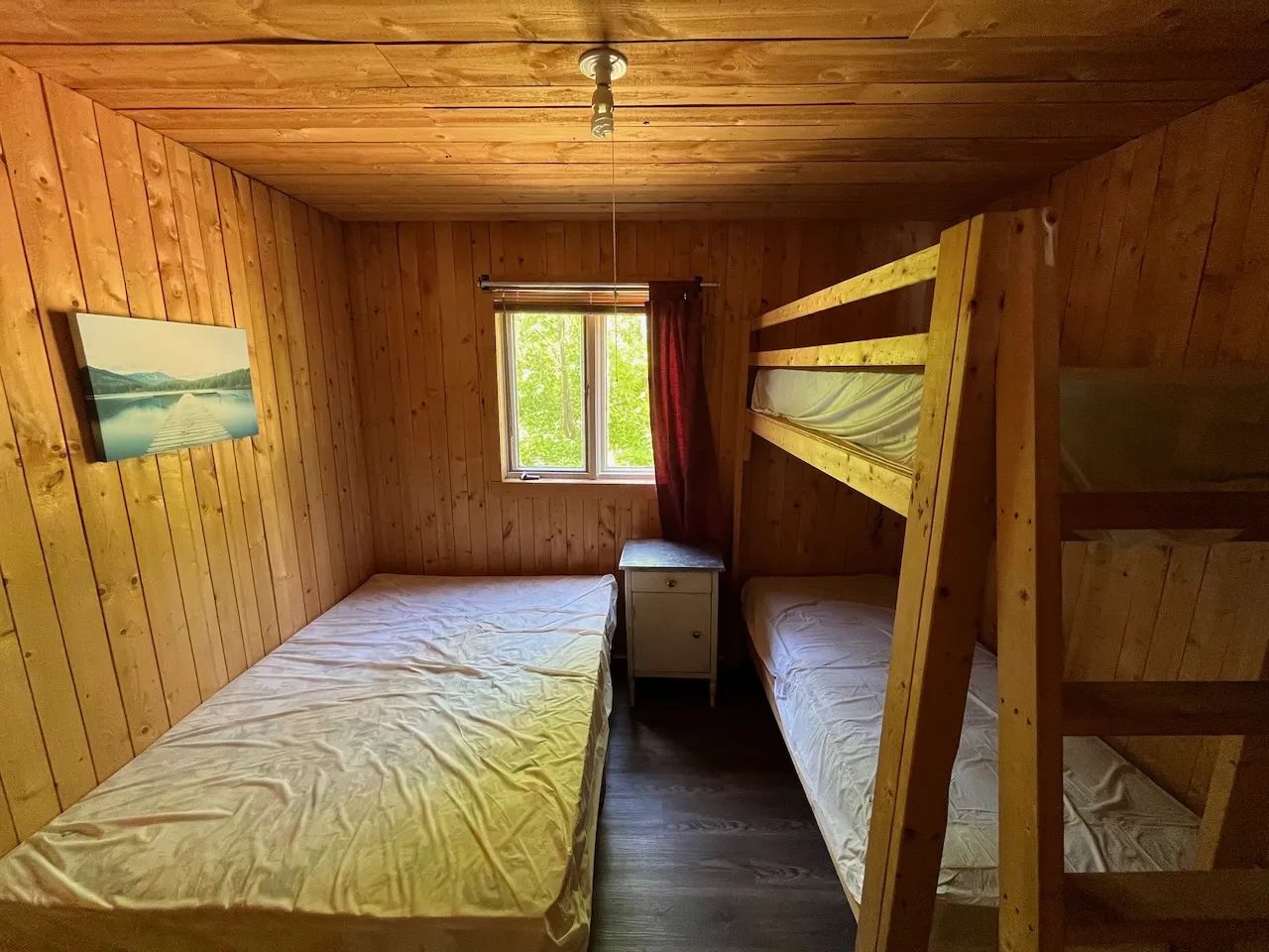 This rustic bedroom in the Pygargue chalet features a single bed and wooden bunk beds.