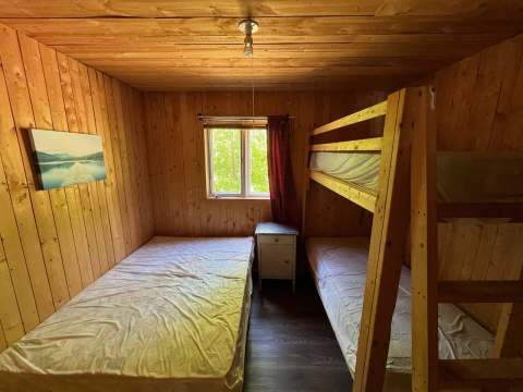 This rustic bedroom in the Pygargue chalet features a single bed and wooden bunk beds.